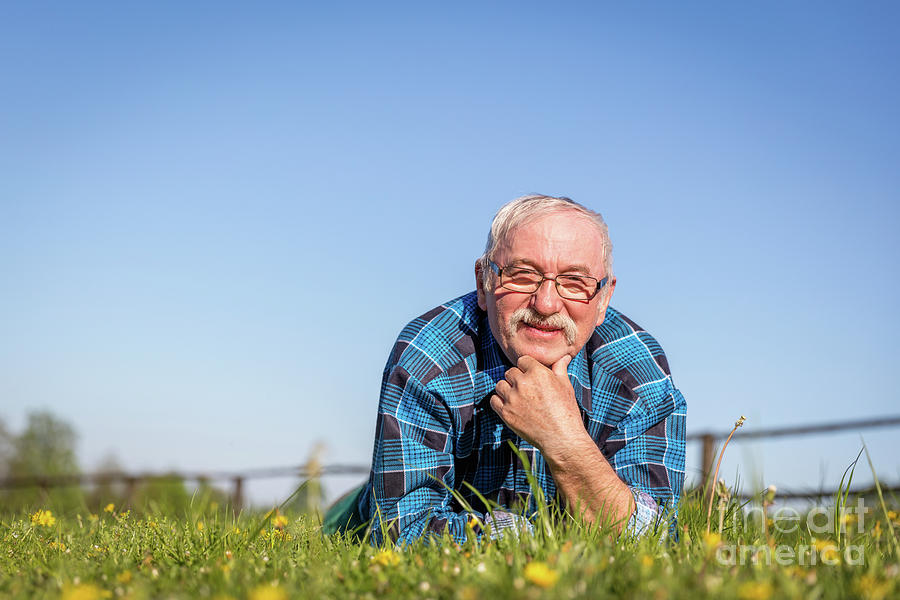 Senior man lying on the summer field in green grass. Photograph by Michal Bednarek