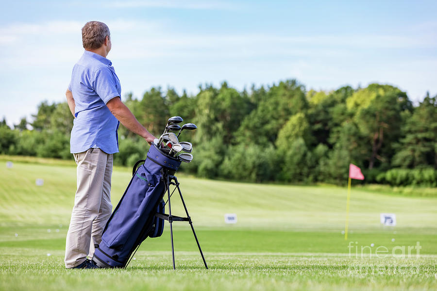 Senior man standing proudly on a golf club. Photograph by Michal Bednarek