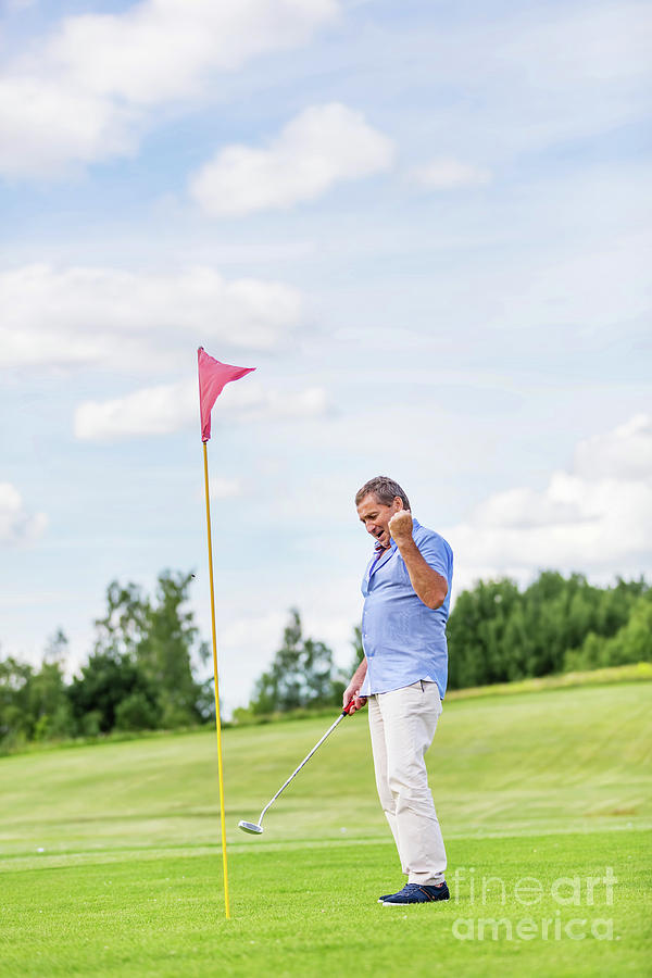 Senior man winning game on a golf course. Photograph by Michal Bednarek