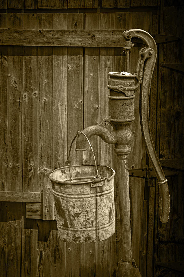 Sepia Toned Rusty Water Pump with Bucket by an old Wooden Barn Photograph by Randall Nyhof