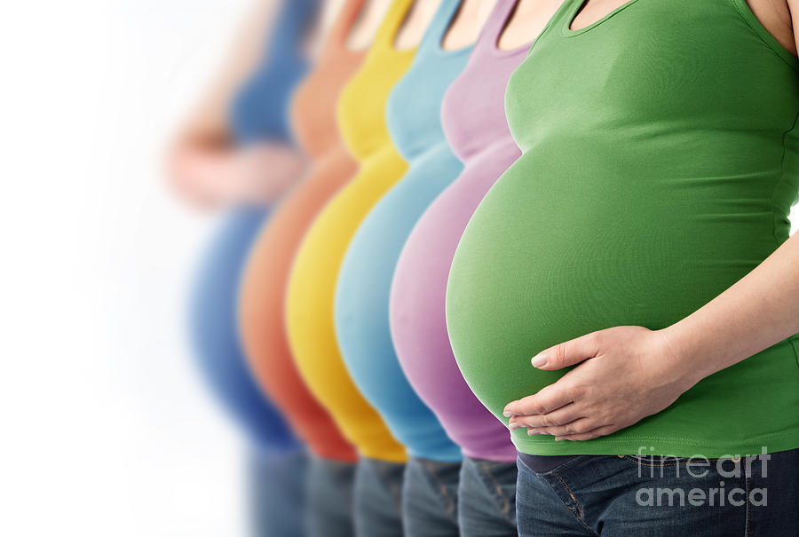 Six pregnant women in different tops standing in a row. Photograph by Michal Bednarek