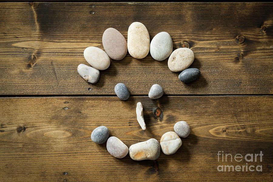 Smiling face made from pebbles on a wooden floor Photograph by Simon Bratt