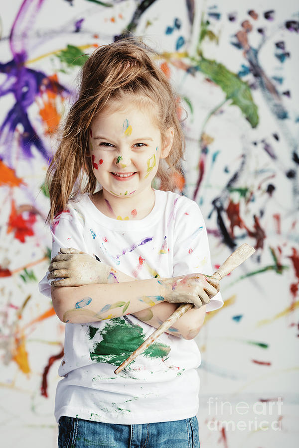 Smiling little girl with painting brush on messy background. Photograph by Michal Bednarek