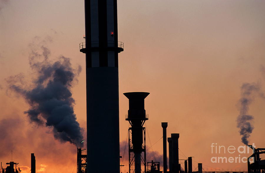 Sunset Photograph - Smoking chimneys of a petroleum refinery at sunset by Sami Sarkis