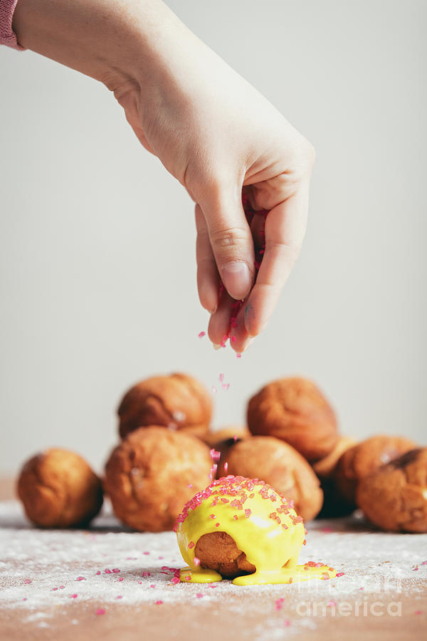 Sprinkling sugar topping on top of a doughnut. Photograph by Michal Bednarek