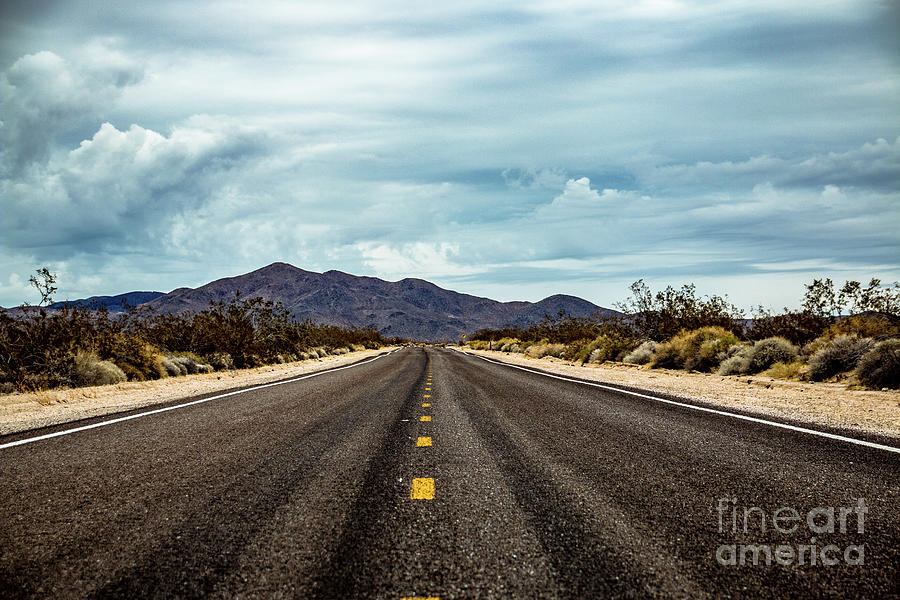 Straight road with mountains in the background and clouds Photograph by Amanda Mohler