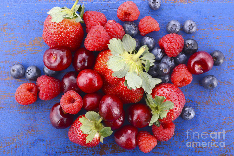 Summer fruit on dark blue wood table.  Photograph by Milleflore Images