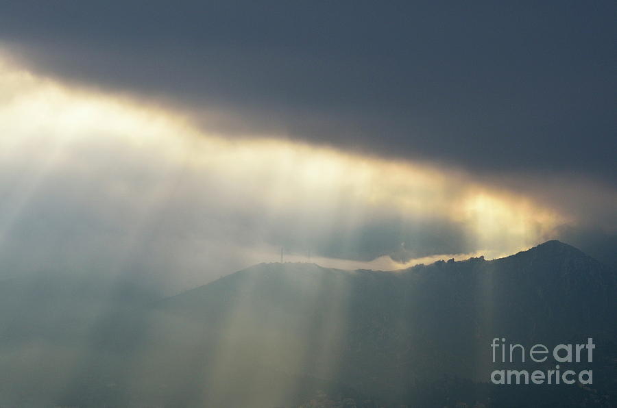 Sunbeams through clouds on mountain range by stormy day Photograph by Sami Sarkis