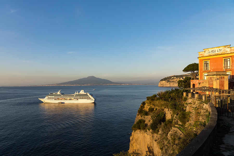 Sunset Postcard from Sorrento - the Sea the Cliffs and Vesuvius Volcano Behind the Criuse Ship Photograph by Georgia Mizuleva