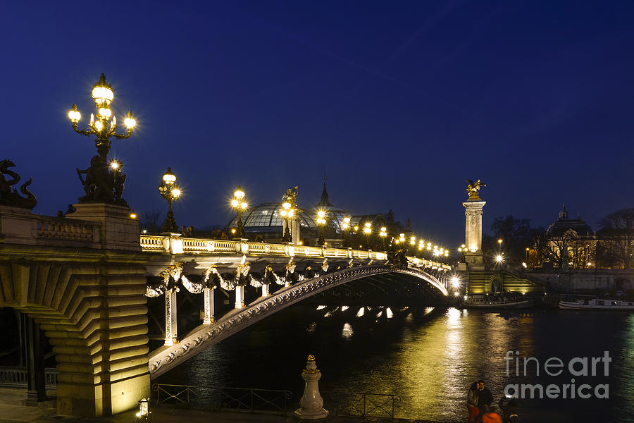 The Pont Alexandre III, arch bridge in Paris at night, Grand Palais behind, France. Photograph by Perry Van Munster