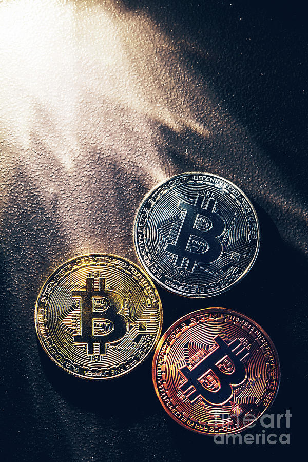 Three colorful bitcoin coins and beams of light. Photograph by Michal Bednarek
