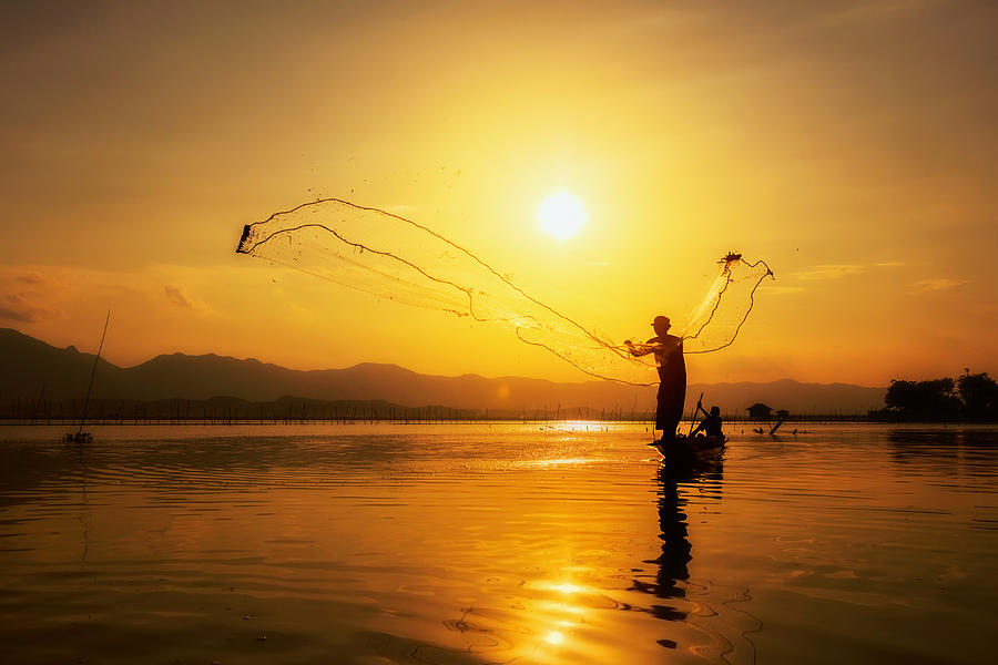 Throwing Fishing Net During Sunset Photograph by Chatrawee