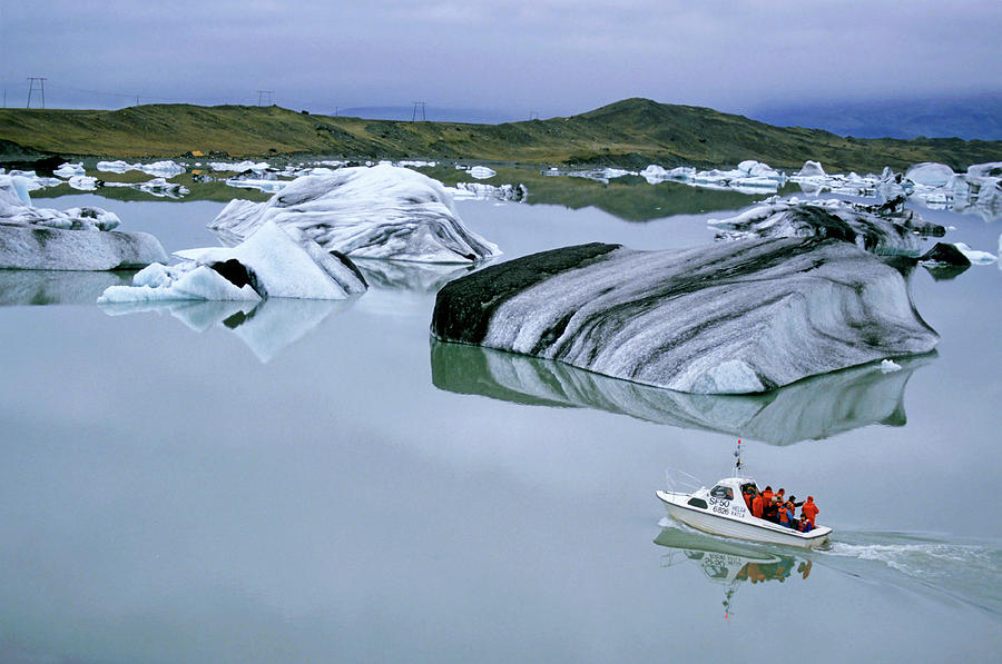 Tourist boat navigating through floating icebergs in the waters of Jokulsarlon Photograph by Sami Sarkis