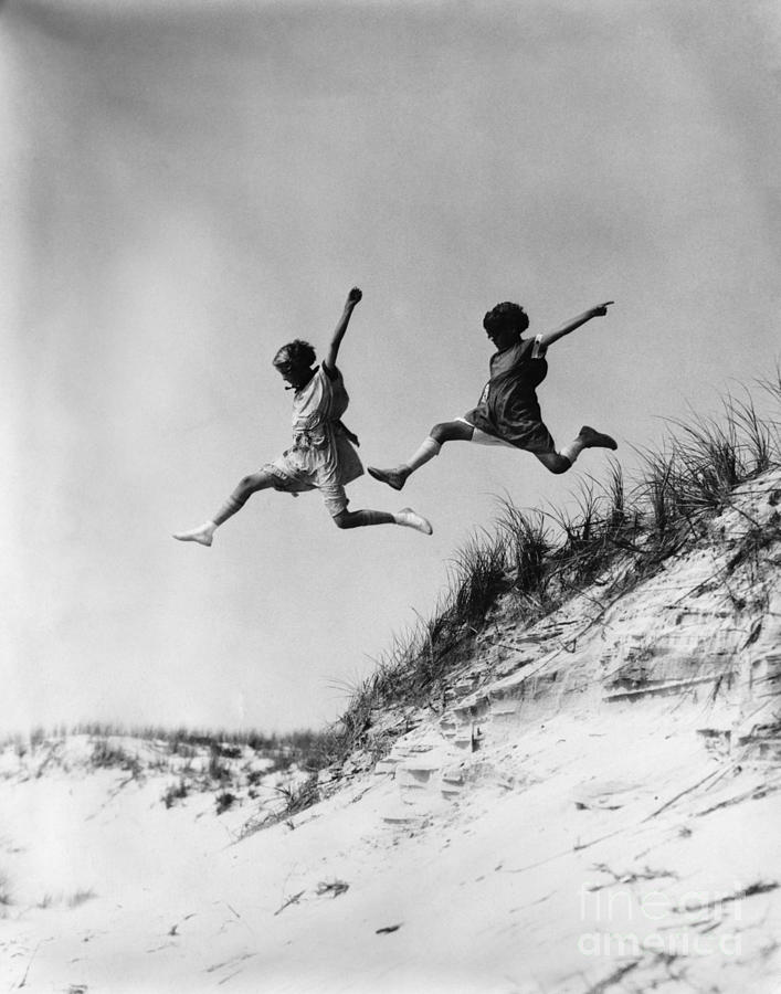 Two Girls Leaping Off Sand Dune Photograph by H Armstrong Roberts and ClassicStock