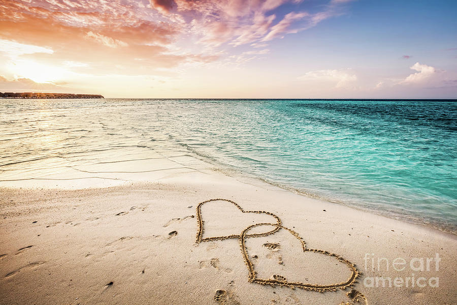 Two hearts drawn on a sandy beach by the sea. Photograph by Michal Bednarek