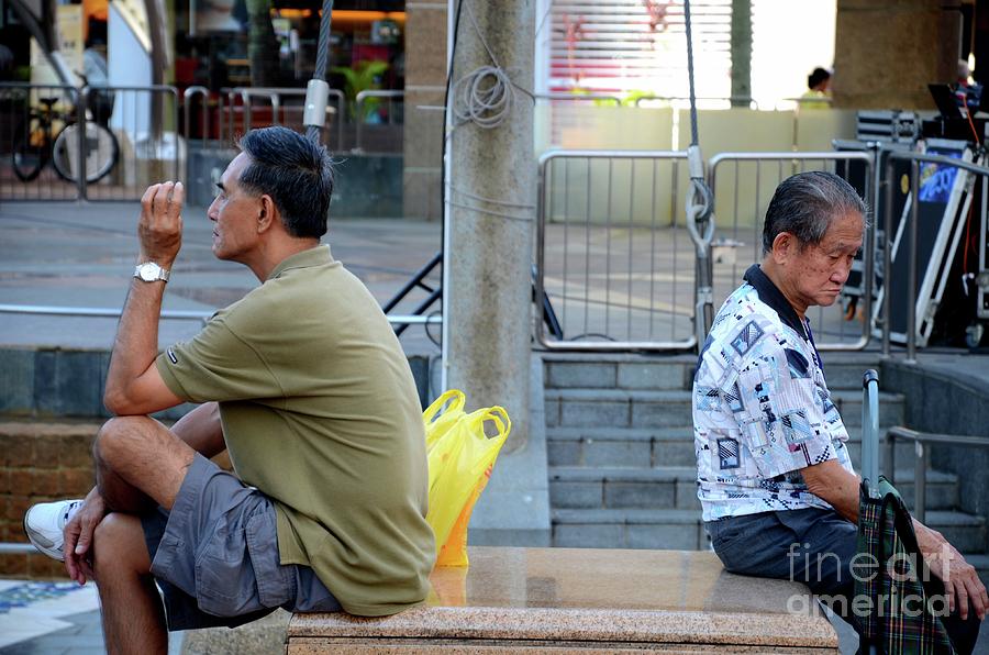 Two men sit back to back in a public square in Singapore Toa Payoh HDB estate Photograph by Imran Ahmed