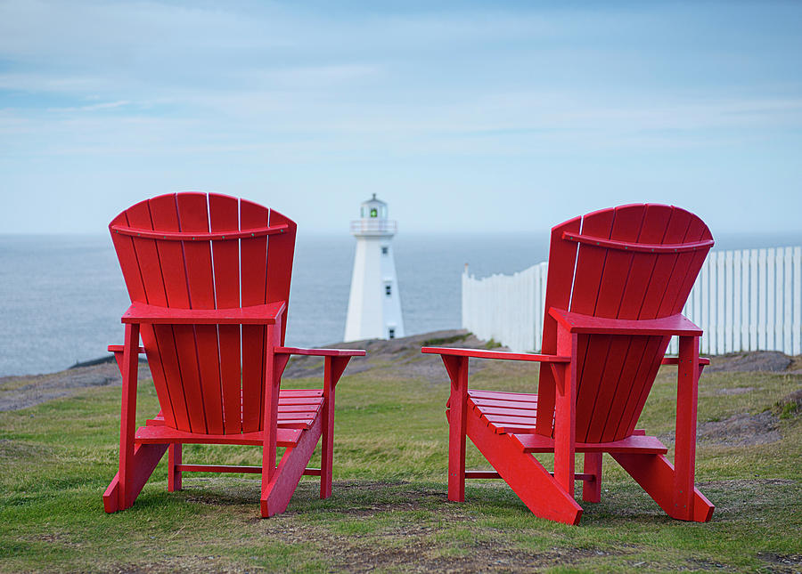 Two Red Adirondack Chairs looking out to a Lighthouse Photograph by Art Whitton