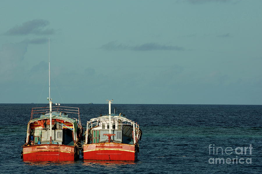 Two red fishing boats moored side by side in the blue ocean Photograph by Sami Sarkis