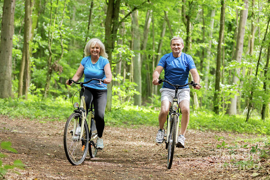 Two senior people cycling in the woods. Photograph by Michal Bednarek