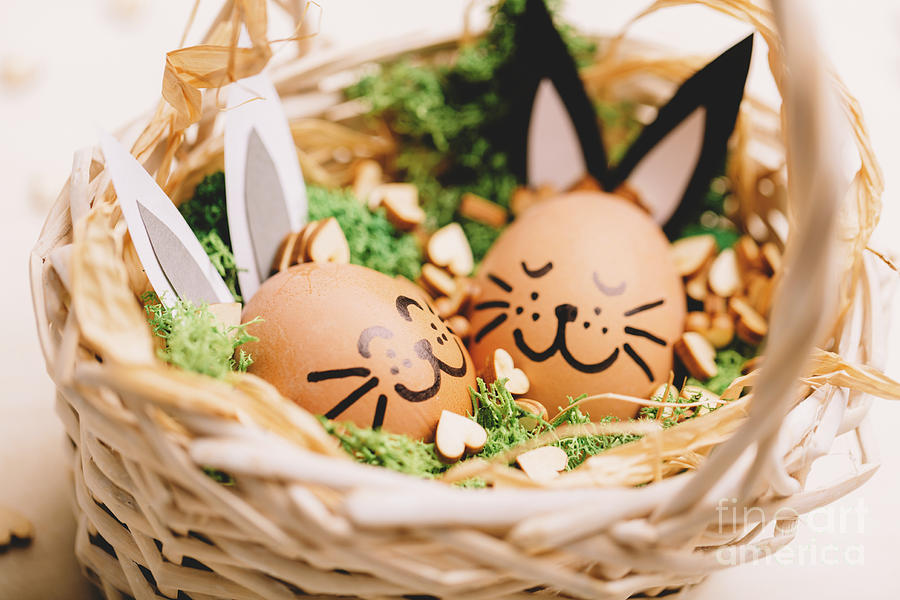 Two smiling egg-bunnies laying in the basket. Photograph by Michal Bednarek