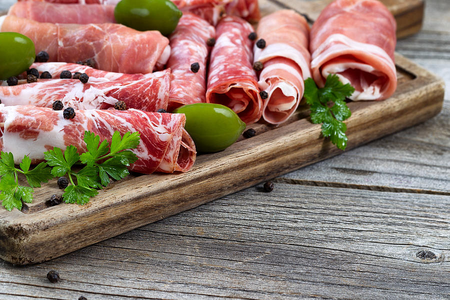 Various raw meats on serving board with rustic background Photograph by ...