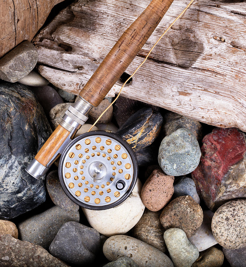 Vintage fly fishing outfit on rocks and wood background Photograph