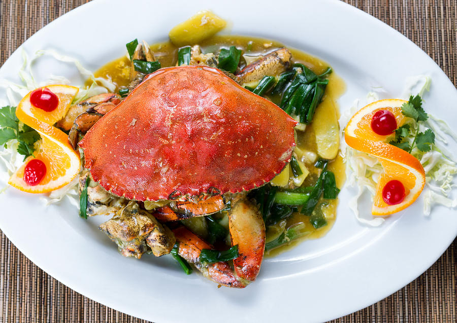 Whole cooked Dungeness crab with green onion sauce on white serv