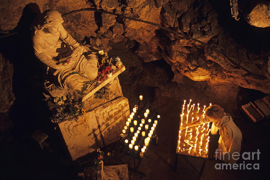 Woman burning candle at Troglodyte Sainte-Marie Madeleine Holy Cave Photograph by Sami Sarkis