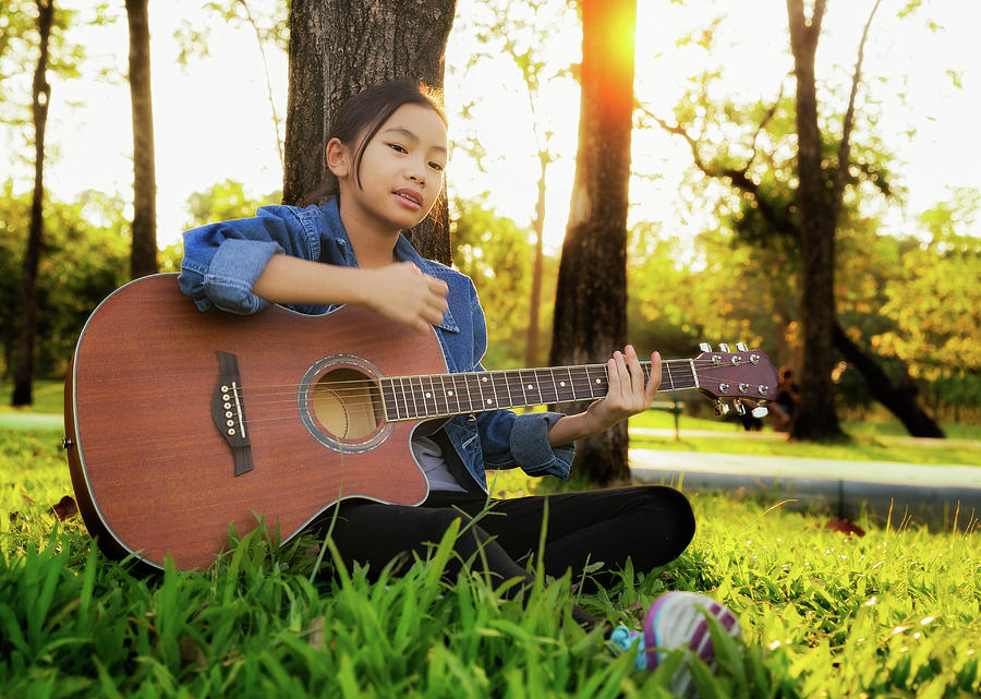 Woman playing guitar in park Photograph by Anek Suwannaphoom
