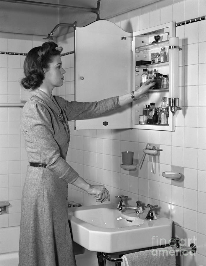 Woman Reaching Into Medicine Cabinet Photograph by H. Armstrong Roberts/ClassicStock