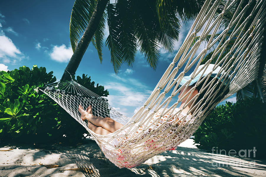 Woman relaxing in the shade of palms on a hammock. Photograph by Michal Bednarek
