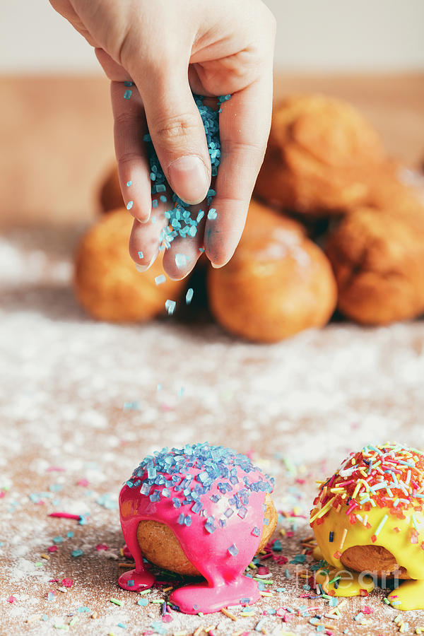 Woman sprinkling sugar strands on doughnuts Photograph by Michal Bednarek