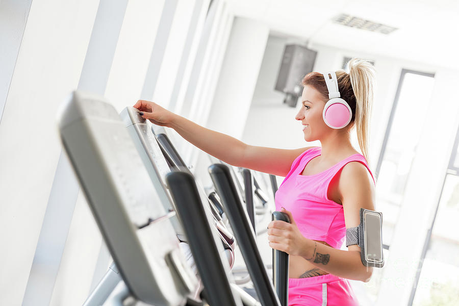 Woman starting crosstrainer workout in a gym. Photograph by Michal Bednarek