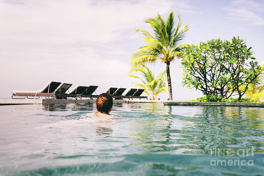 Woman swimming in a hotel pool in a tropical resort. Photograph by Michal Bednarek