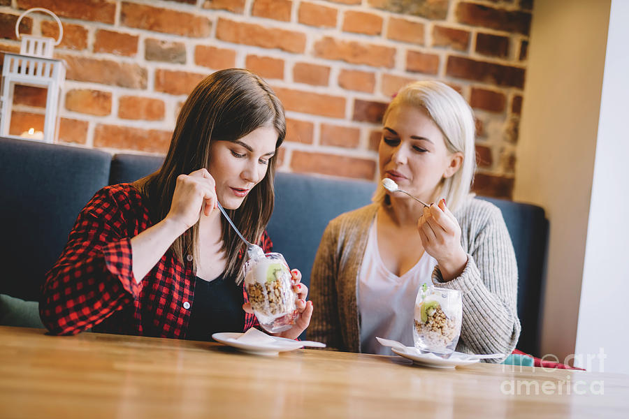 Women eating healthy dessert in a restaurant. Photograph by Michal Bednarek