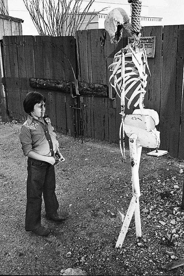 Young boy and hanging skeleton backlot Old Tucson Arizona 1979 Photograph by David Lee Guss