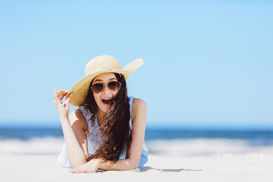 Young enthusiastic girl laying on the beach, smiling. Photograph by ...