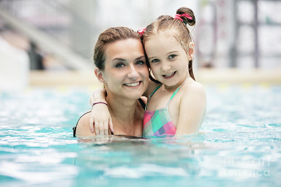 Young girl and her mother hugging in the pool. Photograph by Michal Bednarek