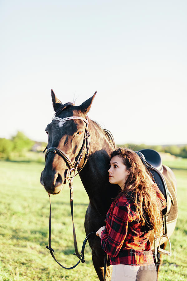 Nature Photograph - Young girl hugging purebred black horse on the field. by Michal Bednarek