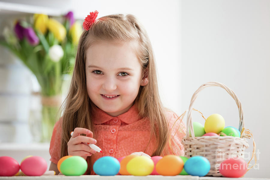 Young girl painting eggs by the desk, smiling Photograph by Michal Bednarek