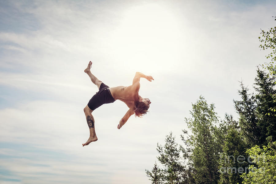 Young Man Doing A Backflip In The Air. Photograph