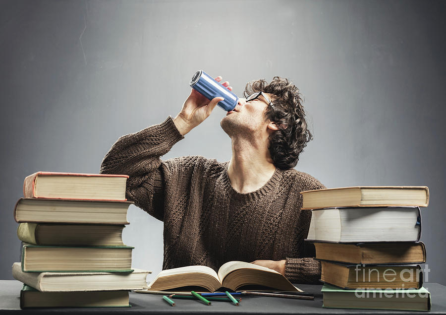 Young man studying and drinking energy drink. Photograph by Michal Bednarek