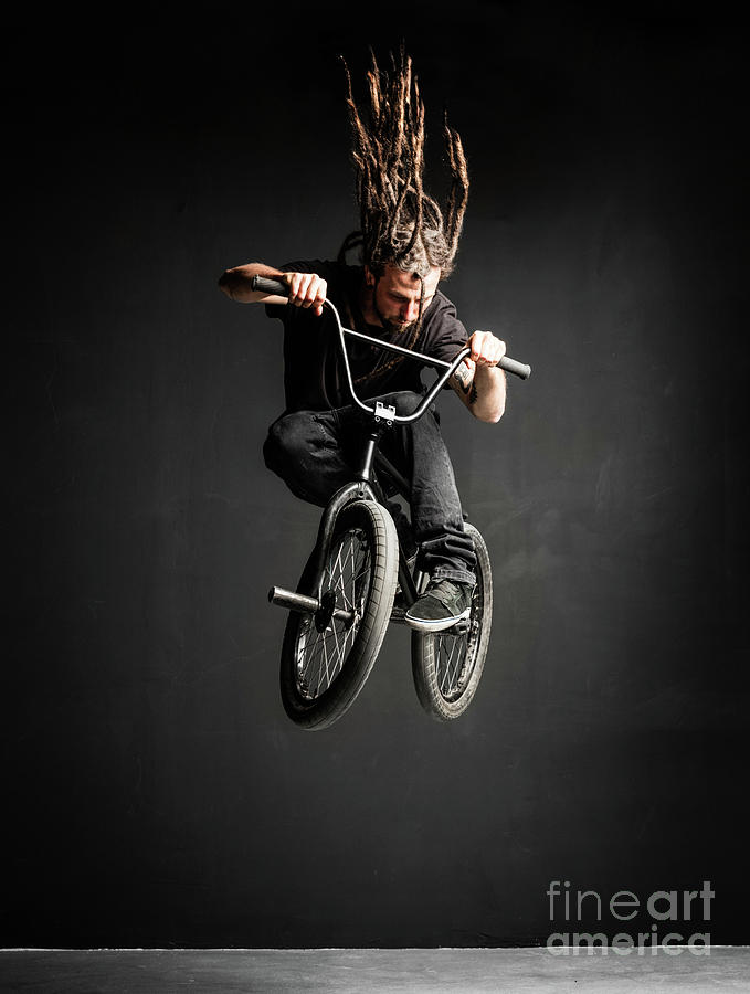 Young man with dreadlocks jumping on his BMX bike. Photograph by Michal Bednarek