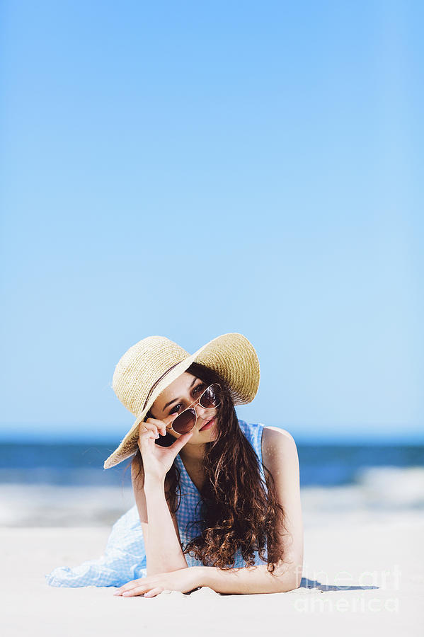 Young pretty woman laying on the beach, holding her sunglasses. Photograph by Michal Bednarek