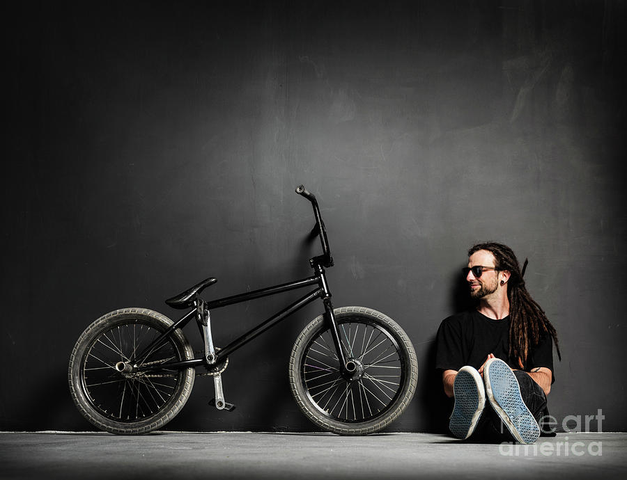 Young smiling man sitting next to his BMX bike. Photograph by Michal Bednarek