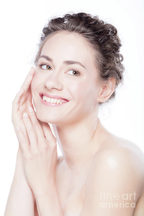 Young smiling woman touching her smooth, healthy face. Photograph by Michal Bednarek