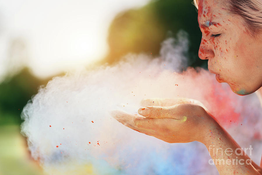 Young woman blowing colorful powder from her hands. Photograph by Michal Bednarek