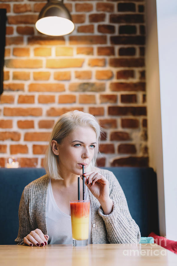 Young woman drinking colorful cocktail. Photograph by Michal Bednarek