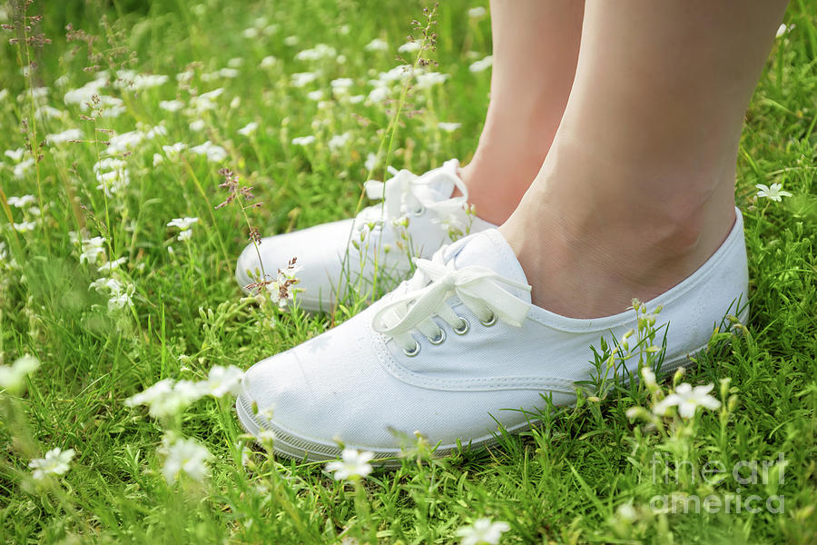 Young woman in white classic sneakers standing in grass on spring ...