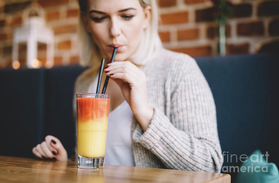 Young woman sipping a healthy smoothie in a restaurant. Photograph by Michal Bednarek